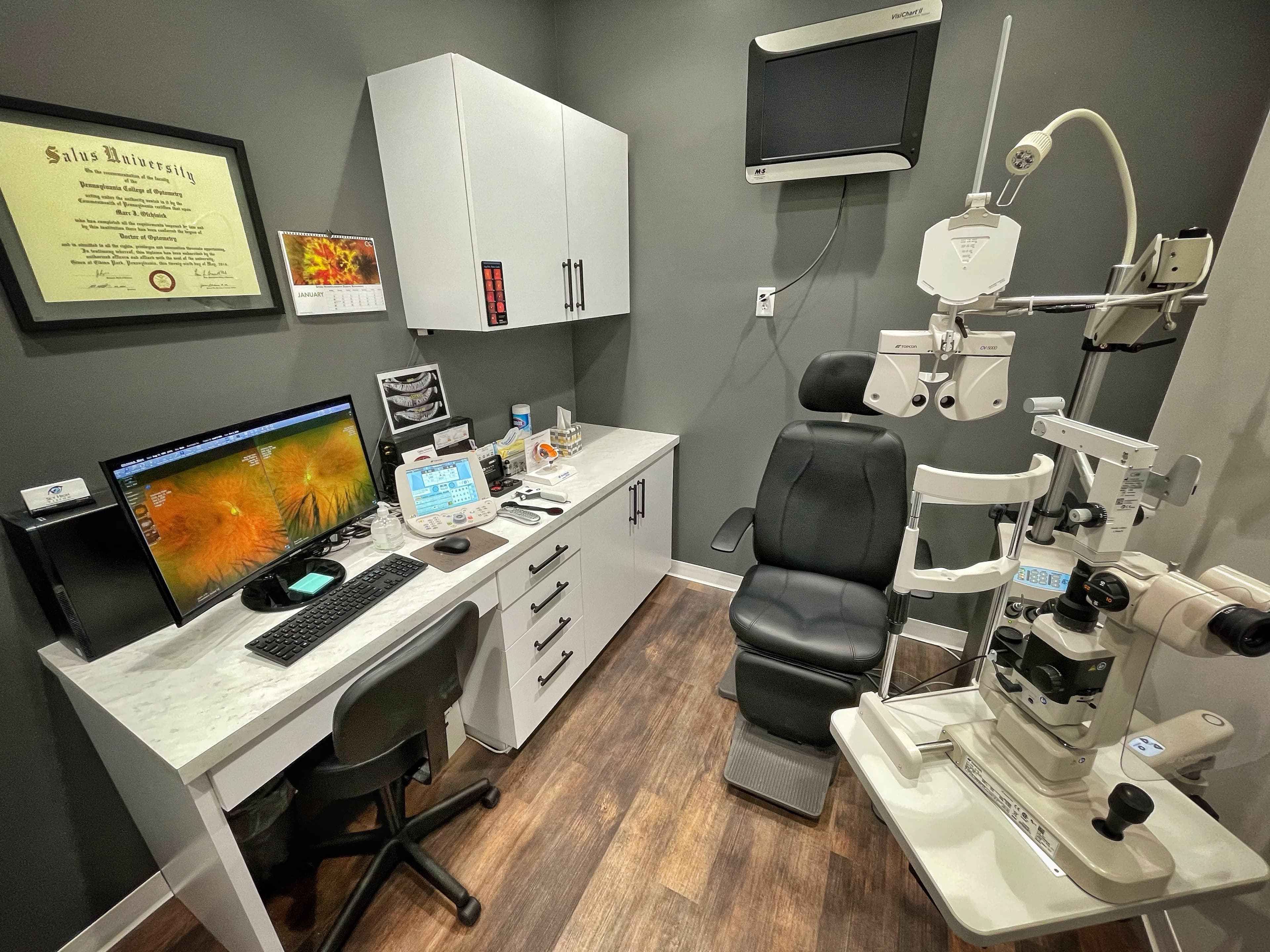 Exam room with the phoropter, slit lamp and a retinal scan on screen